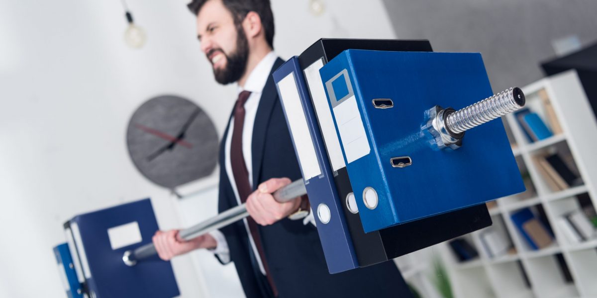 selective focus of businessman weightlifting folders in office