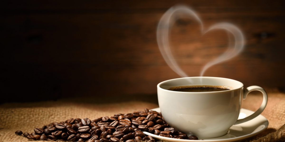 Cup of coffee with heart shape smoke and coffee beans on burlap sack on old wooden background